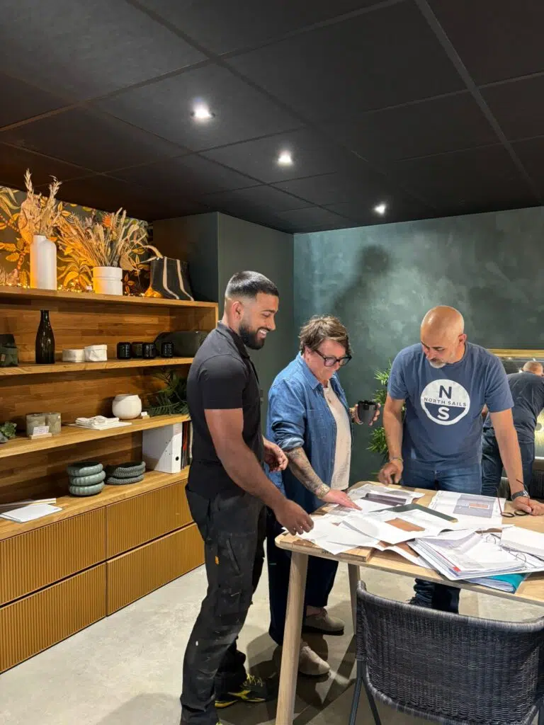 Membres de l’équipe Inside penchés sur des plans et des échantillons de matériaux autour d’une table