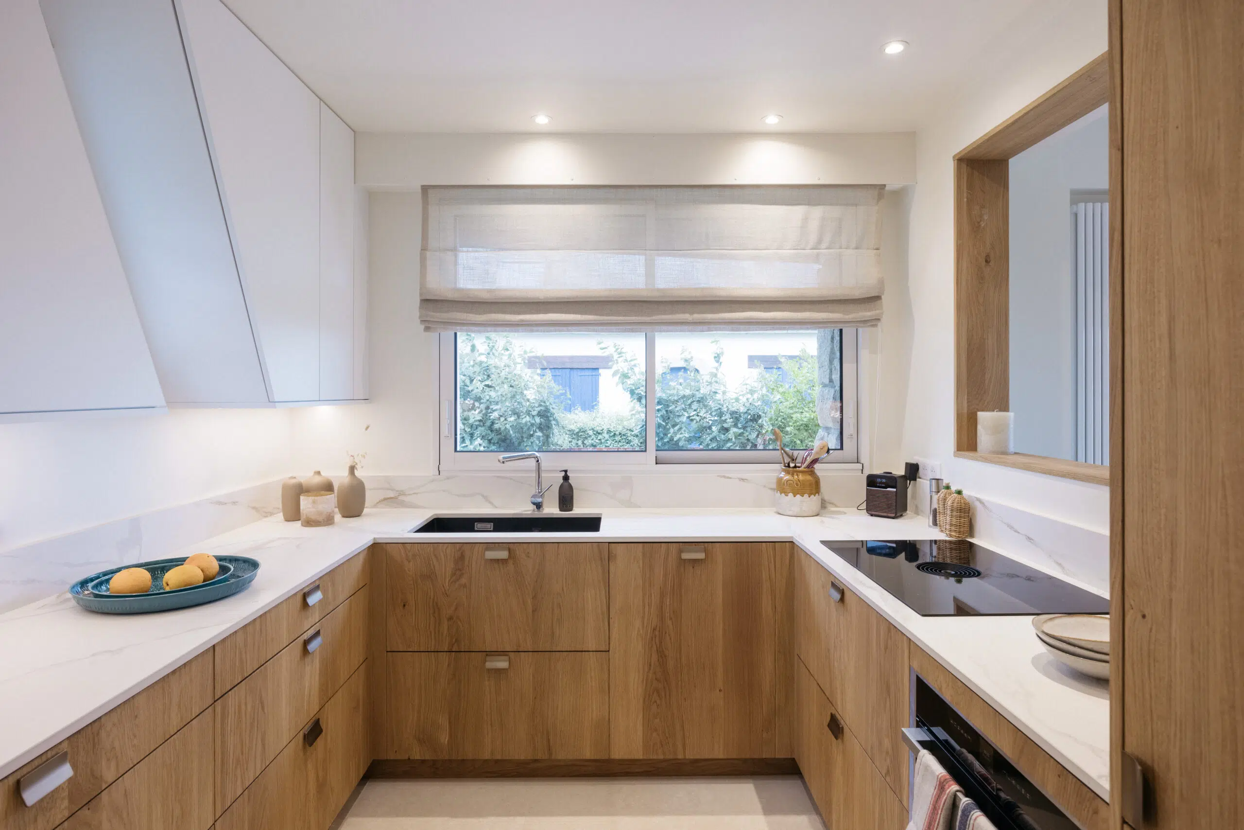 Petite cuisine en U en chêne massif et céramique Calacatta Oro dans une maison de Carnac