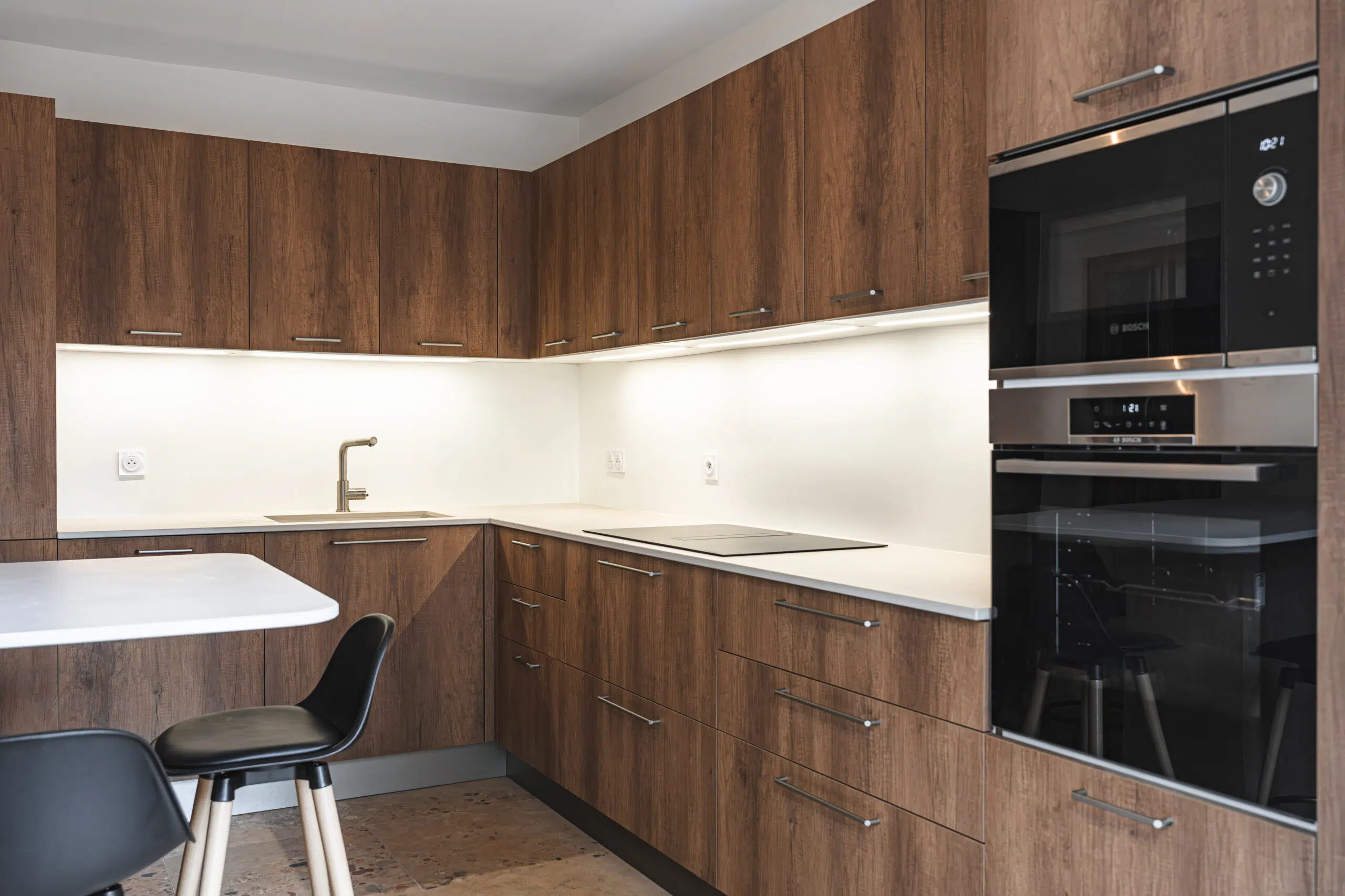 Cuisine sur mesure Warm Balance : façades effet bois aux tons profonds, plan de travail clair et touches de noir