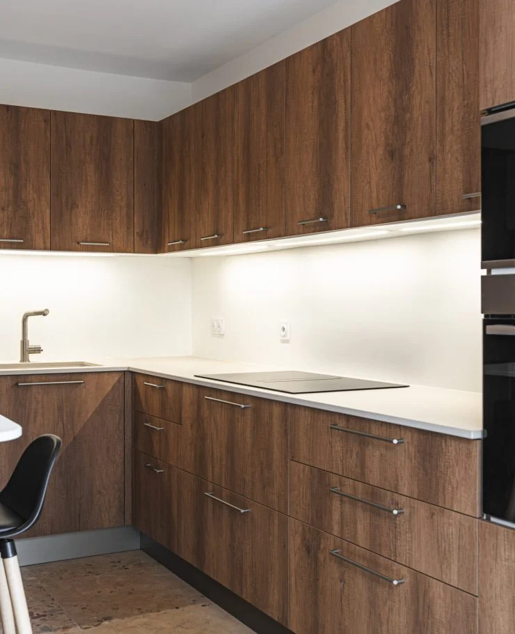 Cuisine sur mesure Warm Balance : façades effet bois aux tons profonds, plan de travail clair et touches de noir