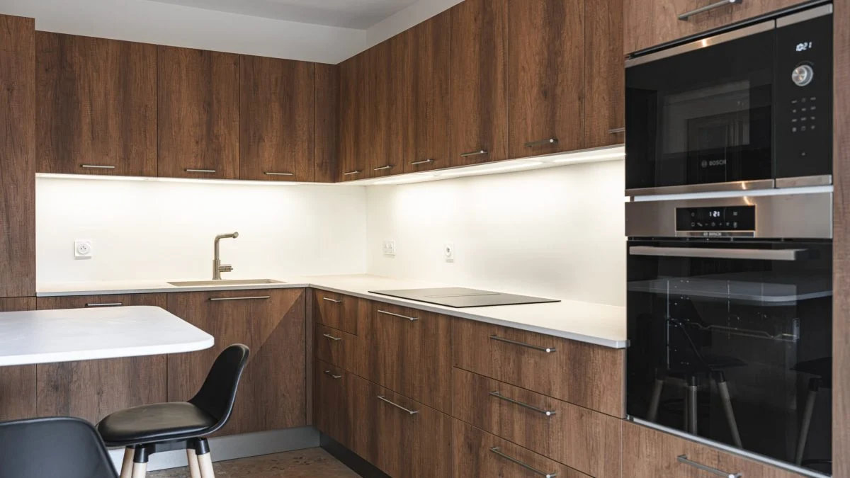 Cuisine sur mesure Warm Balance : façades effet bois aux tons profonds, plan de travail clair et touches de noir