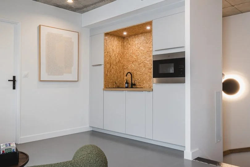 Petite cuisine ouverte en OSB et bois intégrée dans des bureaux professionnels à Plouharnel